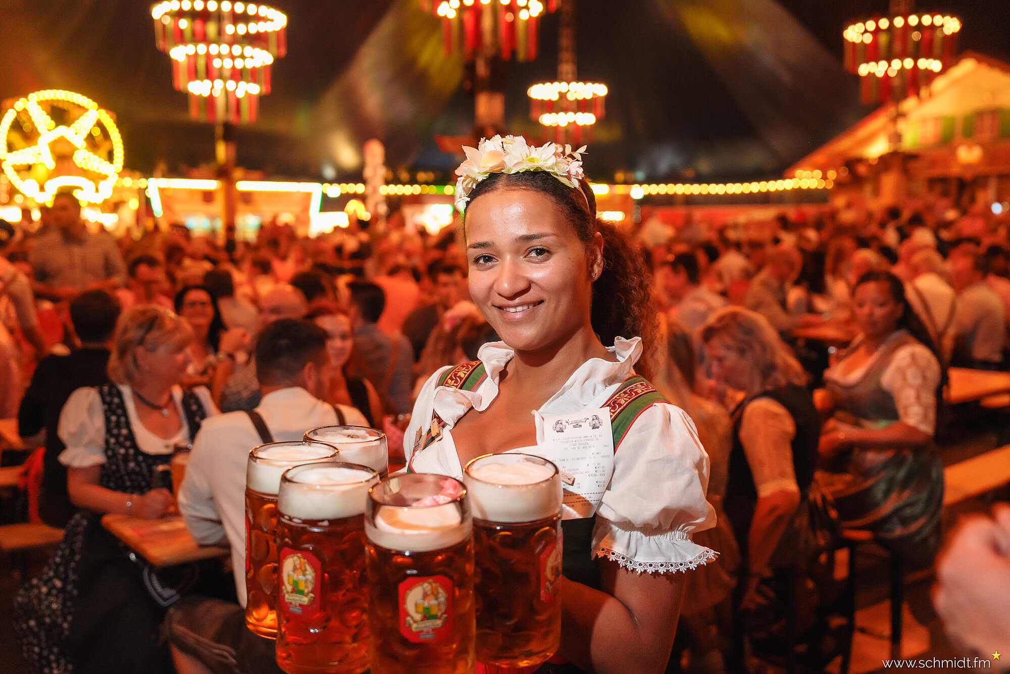 Eine Kellnerin im Dirndl stemmt fünf mit Bier gefüllte Maßkrüge