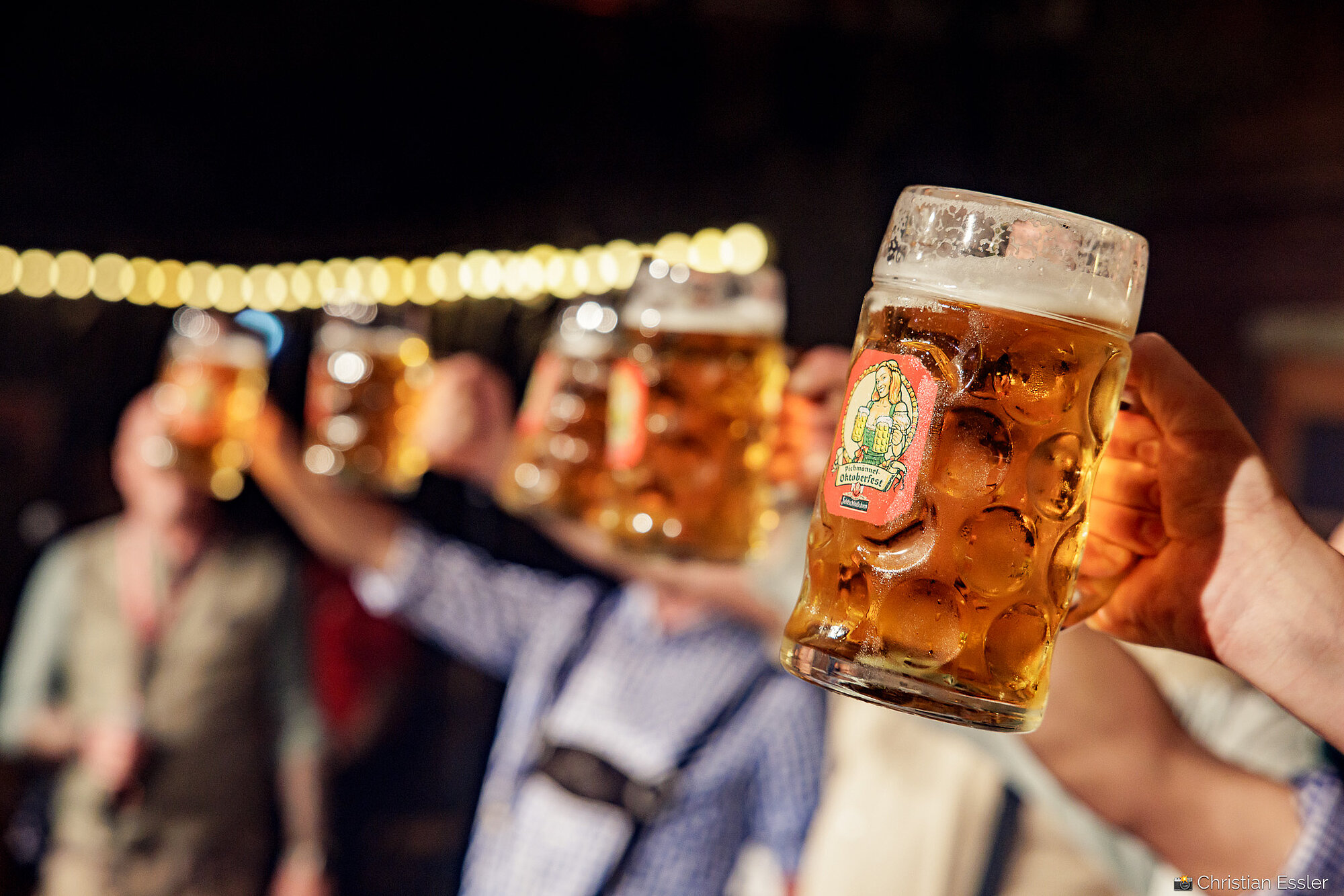 Große Bierkrüge aus Glas, gefüllt mit goldenem Bier, die von starken Armen gestemmt werden