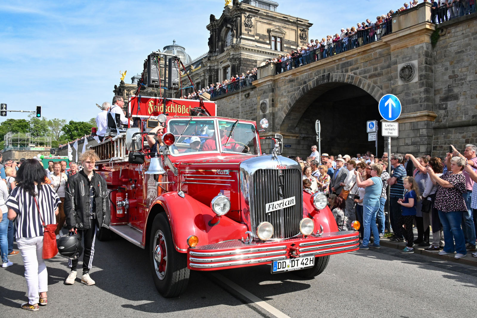 Eine bunte Parade mit Jazzmusikern in traditionellen Outfits zieht durch Dresdens Altstadt, begleitet von der alten Feldschlößchen-Feuerwehr und winkenden Zuschauern