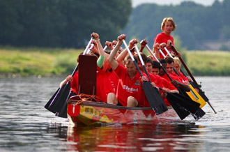 Das Feldschlößchen Team im rot bemaltem Drachenboot paddelt durch das Wasser