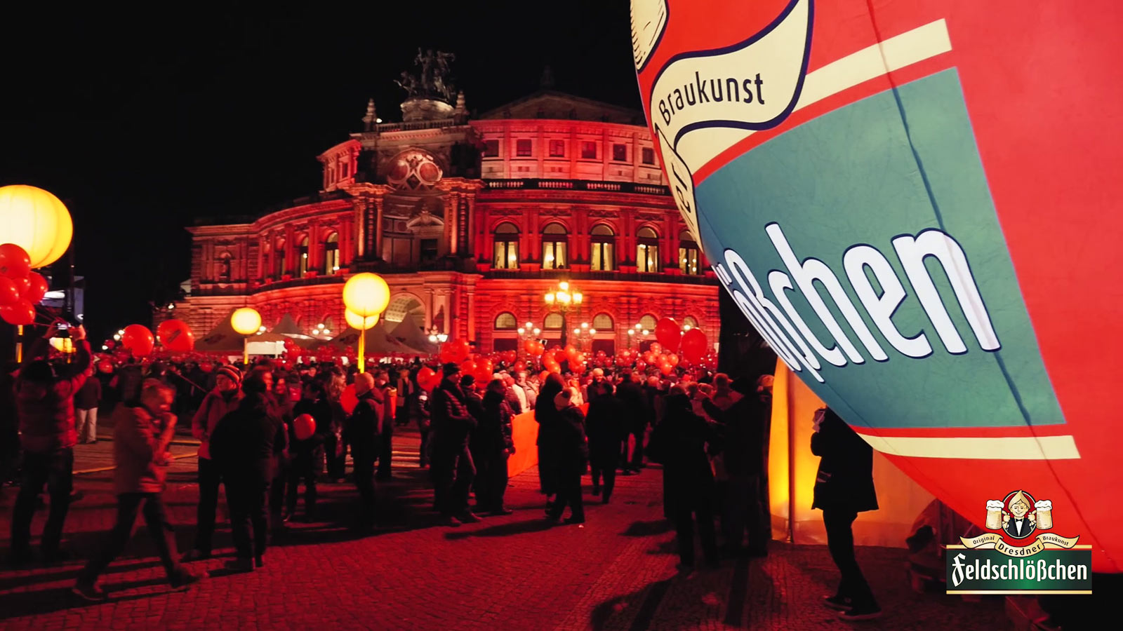 Menschen vor der rot beleuchteten Semperoper mit roten Ballons in der Hand